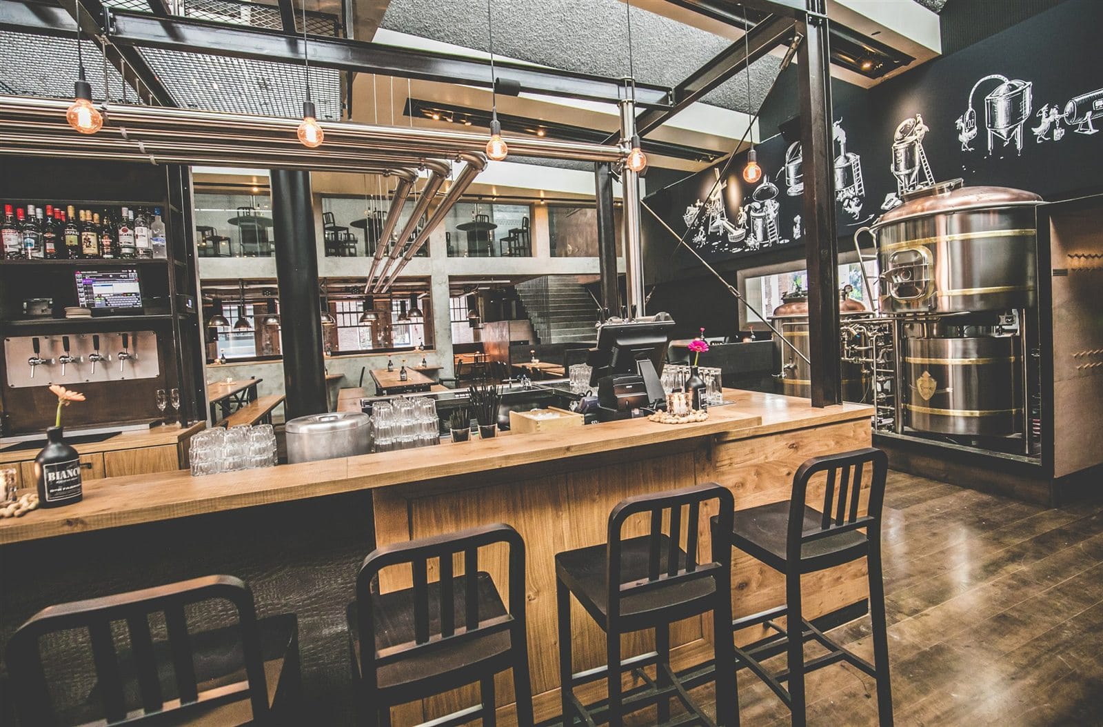 Bierfabriek bar interior with timber bar fronts, black steel, brewery tanks and wall graphics