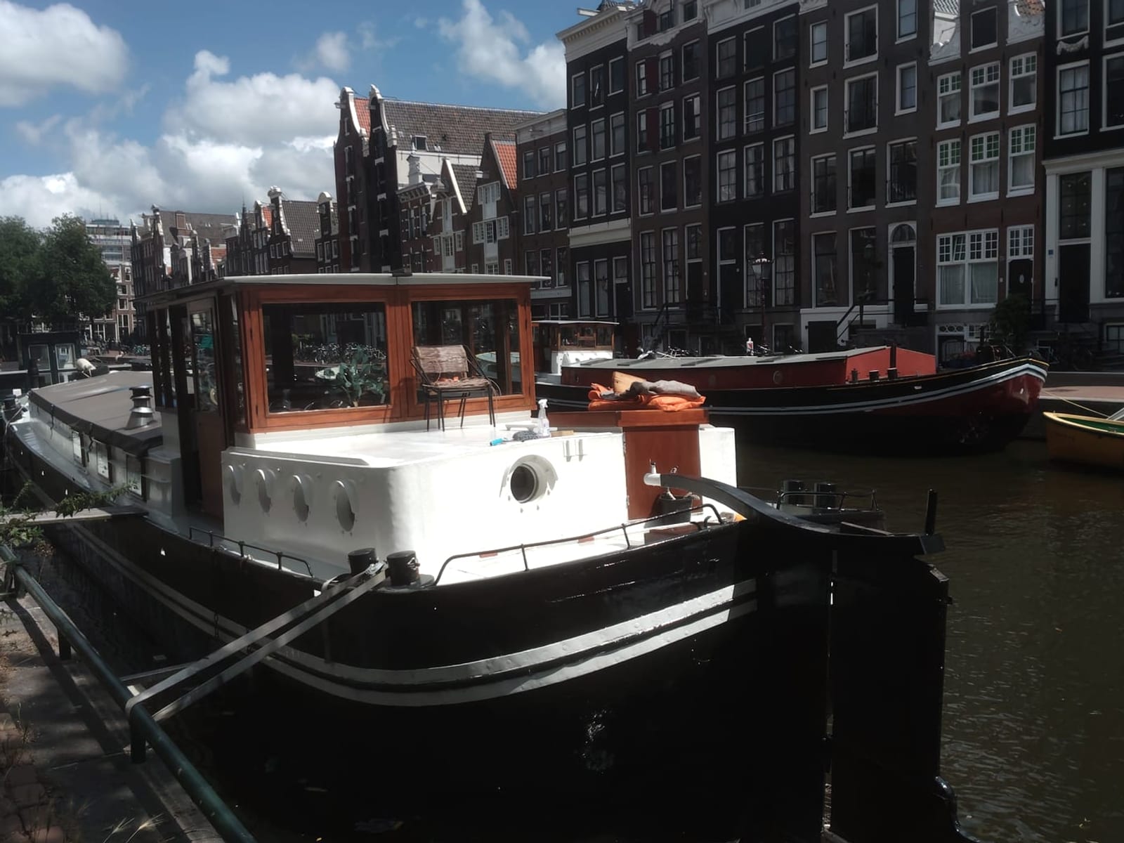 Completed black and white boat moored beside Amsterdam canal houses