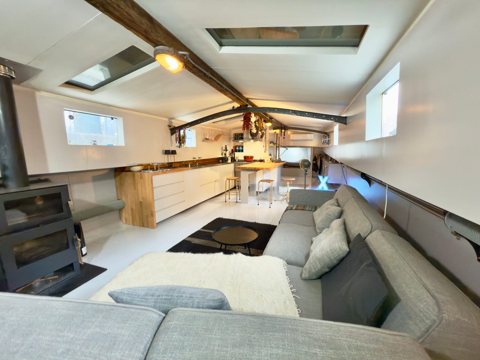 Complete boat interior with fitted kitchen, timber worktops, exposed steel structure and a lounge area