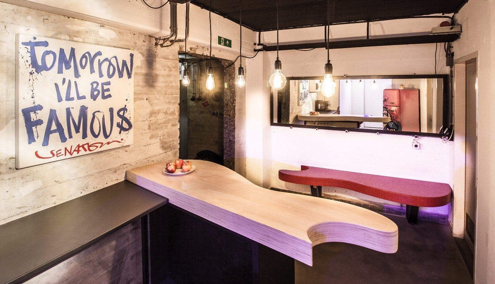 Custom plywood desk with a curved end, red bench, mirror and pendant lights in the Cruise Control studio